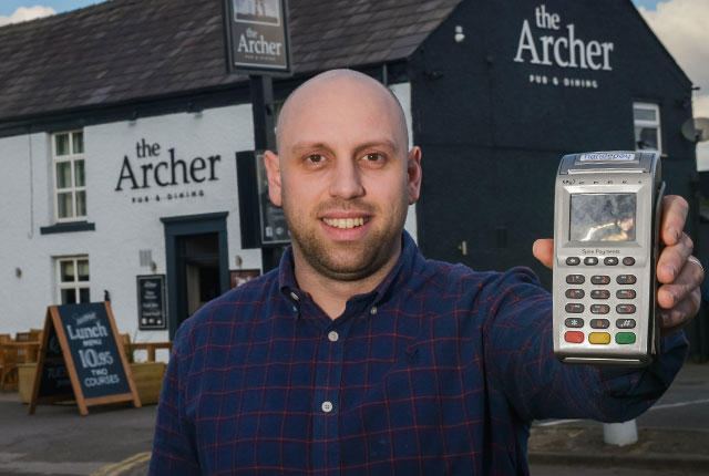 Mark Bayley, owner of The Archer, holding Handepay Card Machine he switched too
