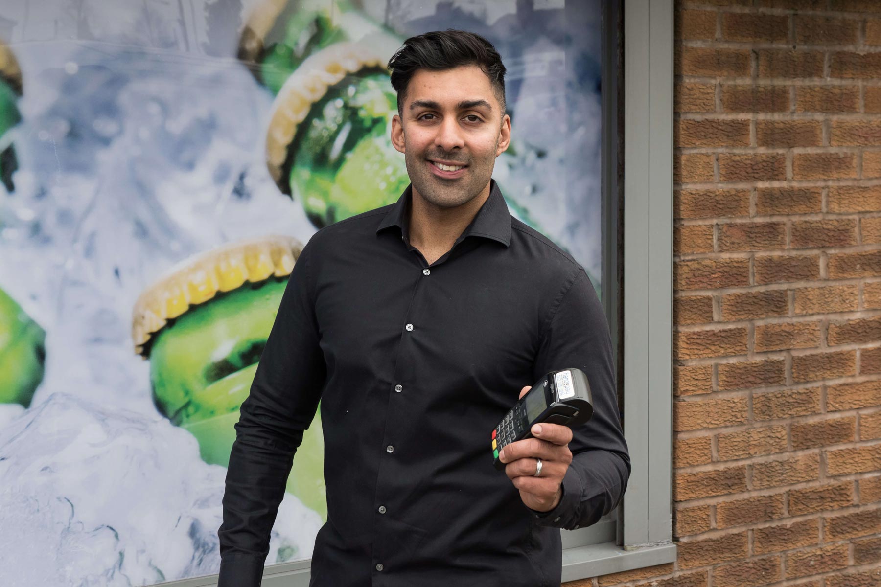 Owner Rocky Sandhu holding Handepay Card Payment Machine