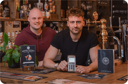 Pub staff behind the bar holding a Handepay Card Payment Machine