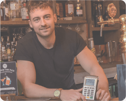 Owner of a pud behind the bar holding Handepay Card Payment Machine