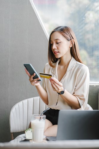 Woman holding payment card whilst looking at her phone