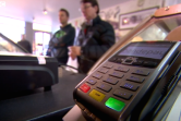 People at payment counter with a contactless payment machine on display