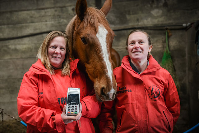 Nichola Whiteside, owner of Cae Hic Livery and Riding Centre smiling whilst holding her Handepay Card Machine
