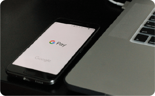 Google Pay on phone next to a laptop
