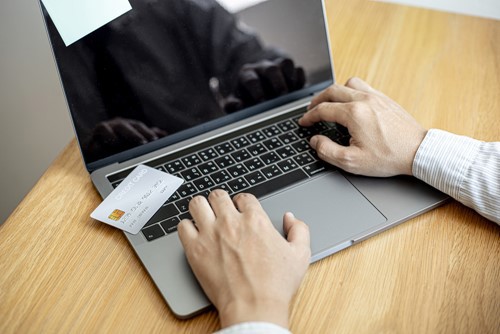 Person using laptop with credit/debit card resting on keyboard